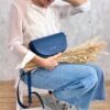 Indigo blue Alma bag from The Code in close-up on the sitting model